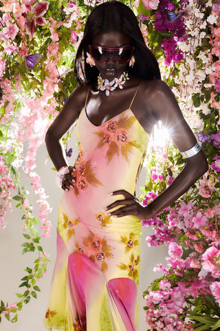 Woman in a floral dress standing amidst flowers. Cybersweeties model in a colourful dress lying on a water tank with floral decorations.  y2k & 2000s. The Coral cocktail gown - Limited edition hand painted
